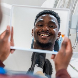 Man smiling at reflection in handheld mirror