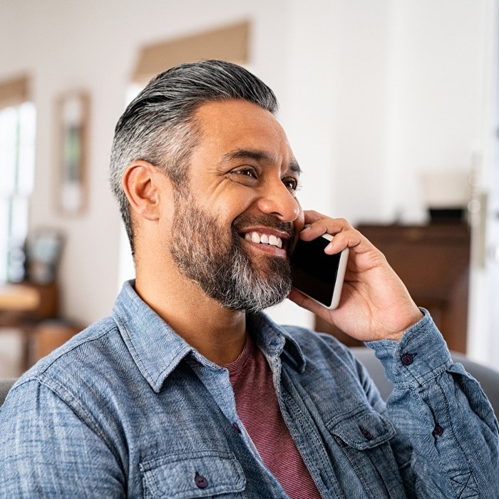 Man smiling while talking on phone at home