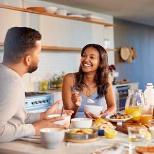 Couple smiling at each other while eating in kitchen