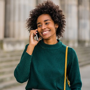 Woman smiling while talking on phone outside