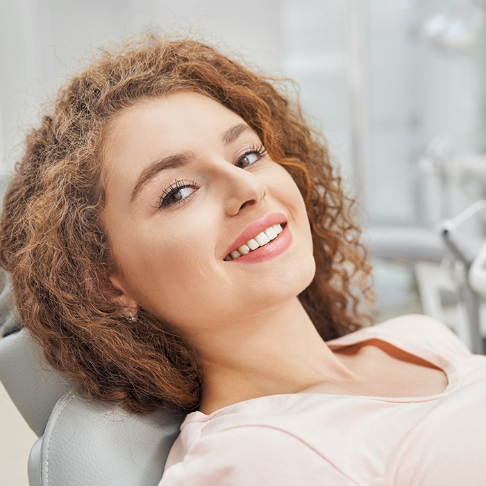 Smiling woman leaning back in the dental chair