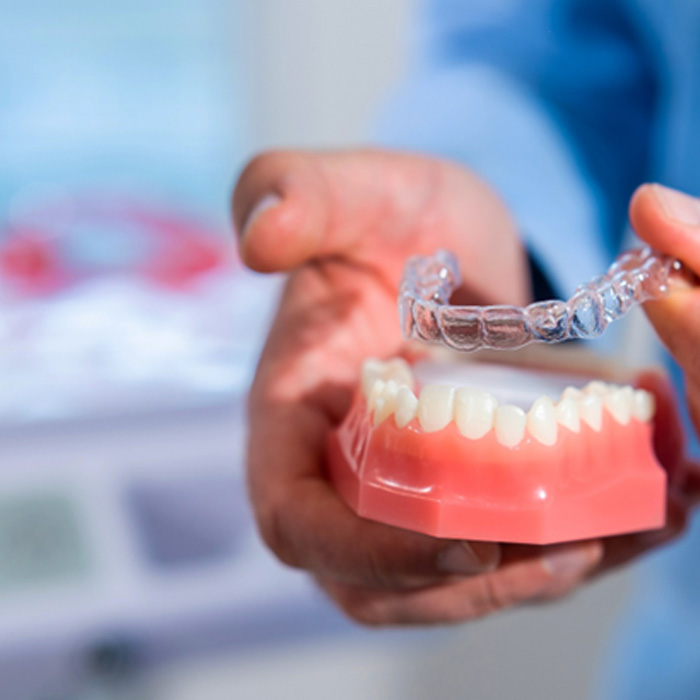 Dentist placing Invisalign over sample teeth