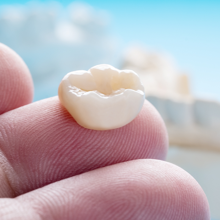 Close up of a dental crown resting on a finger