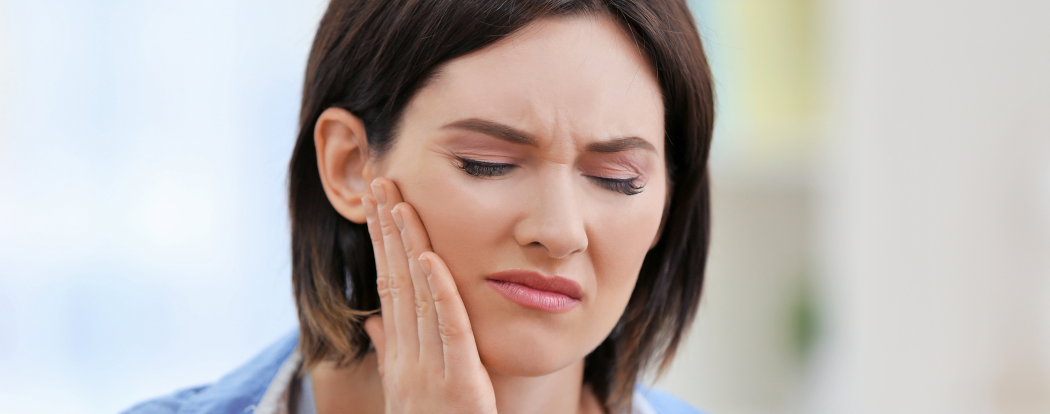 Woman holding her cheek in pain before root canal treatment in Sterling Heights
